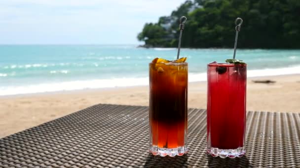 Kall apelsin och hallon cocktails på bordet på stranden, soligt hav på bakgrunden — Stockvideo