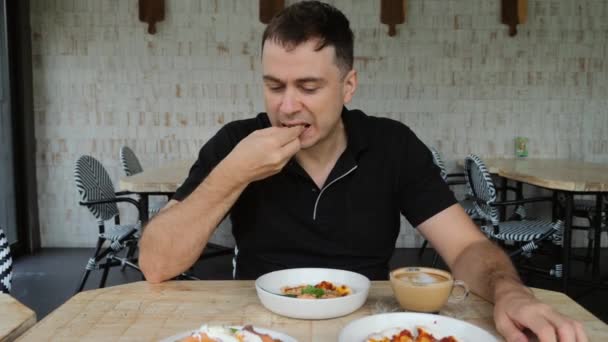 Mann isst Pizzen im Cafe, nimmt ein Handy, um soziale Medien zu überprüfen — Stockvideo