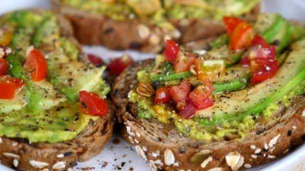 Begreppet hälsosam mat - avokado toast med tomat och svartpeppar — Stockvideo