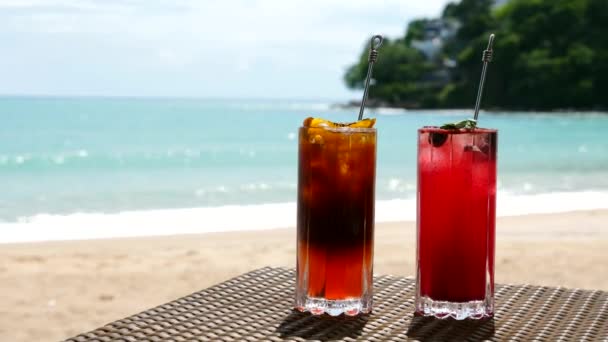 Dos bebidas refrescantes en la mesa con el mar en el fondo — Vídeos de Stock
