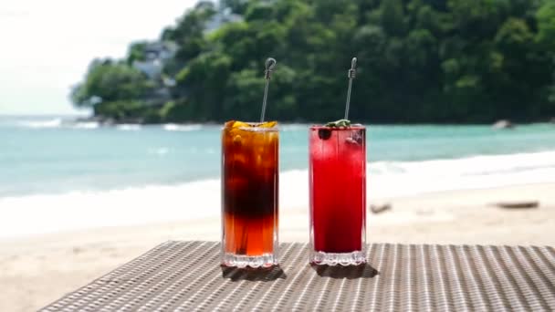 Hermosos cócteles refrescantes de frutas en la mesa en la playa, mar azul en el fondo — Vídeos de Stock