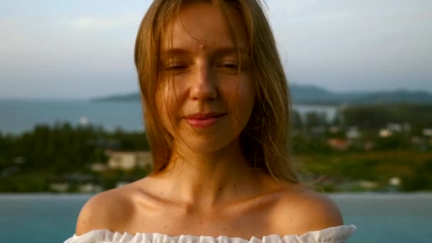 Jong glimlachende vrouw kijken naar camera en staan op het dak op zonsondergang — Stockvideo