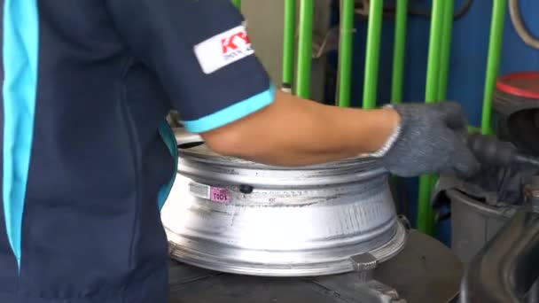 Специалисты шинного центра за рабочим процессом, снимают колесный диск со смены шин — стоковое видео