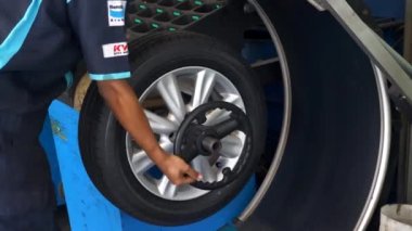 Otomobil Servis Uzmanı Tekerlek Dengeleyicisine Yeni Bir Araba Lastiği Bağlıyor