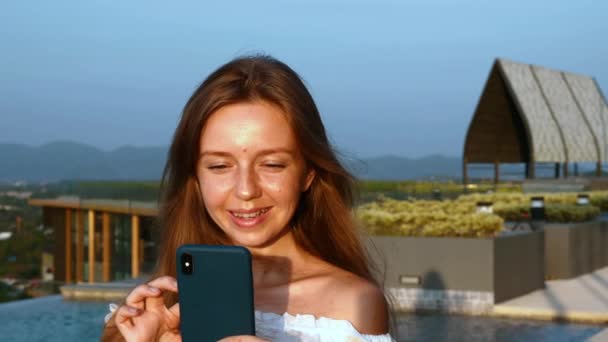 Αργή κίνηση της νεαρής χαμογελαστή γυναίκα με Smartphone κύλιση Social Media — Αρχείο Βίντεο