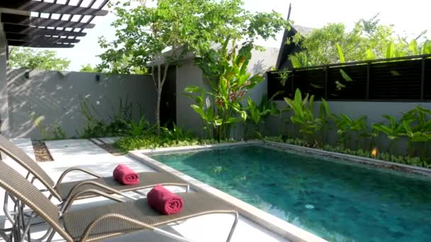 Chaises longues avec serviettes de bain sur terrasse avec piscine bleue et jardin dans la maison — Video