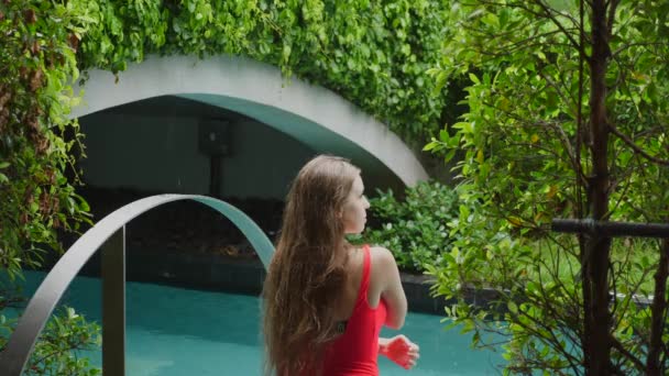 Fürdőruhás nő az úszómedencében esőben, meditálva és élvezve a frissességet — Stock videók