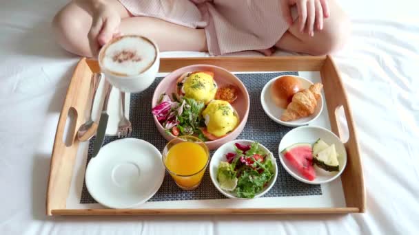 Mulher mão coloca xícara de café no café da manhã na cama servida com salada, frutas frescas — Vídeo de Stock