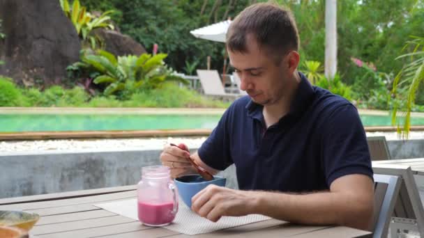 健康适当的营养，青少年在热带咖啡屋内享用水果冰沙碗 — 图库视频影像