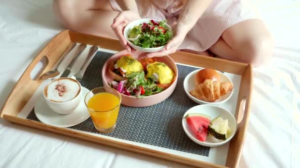 Café da manhã na cama, bandeja com xícara de café, croissants, ovos e suco de laranja — Vídeo de Stock