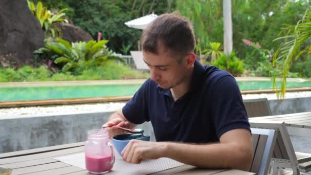 Jovem sonhando Pensive Man come saudável comida frutas tigela, olhando para cima em algum lugar — Vídeo de Stock