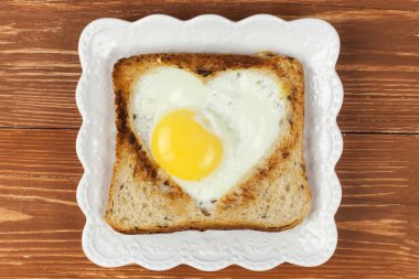 Kalp şekli tam yumurta beyaz tabakta dışarı kesim ile tahıl tost ekmek dilimi