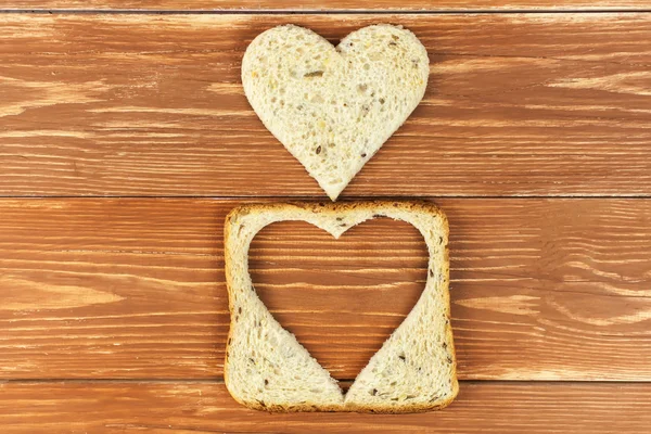 Rebanada de pan tostado de cereales con forma de corazón cortado sobre fondo de madera — Foto de Stock