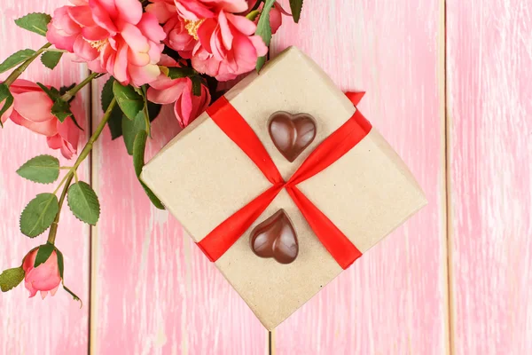 Συσκευασία δώρου με κόκκινη κορδέλα, καραμέλα και ροζ λουλούδια. Επιλεκτική εστίαση. — Φωτογραφία Αρχείου