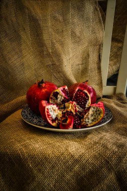 Tahta bir masada, tabakta taze kırmızı nar.