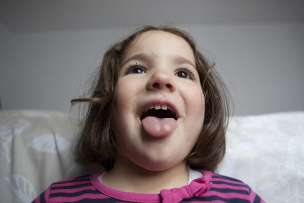 Spaßvogel dreijähriges kleines Mädchen mit herausgestreckter Zunge — Stockfoto