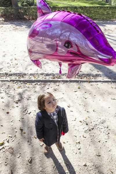 Little girl holding a big balloon dolpin shaped — Stock Photo, Image