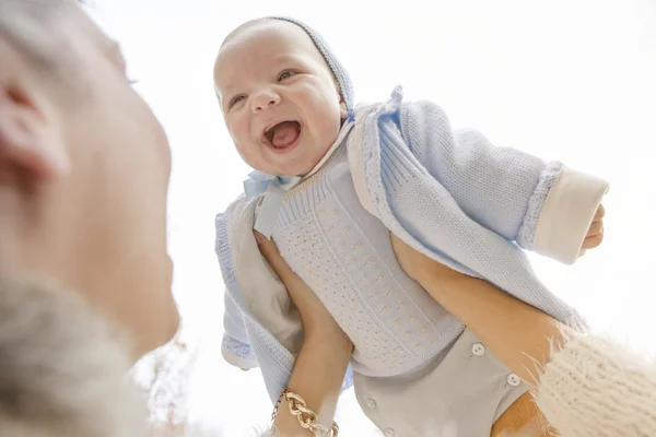 Feliz madre jugando con su bebé en el parque en el banco en w — Foto de Stock