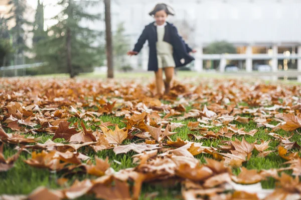 Appy niña jugando con las hojas de otoño en el parque — Foto de Stock