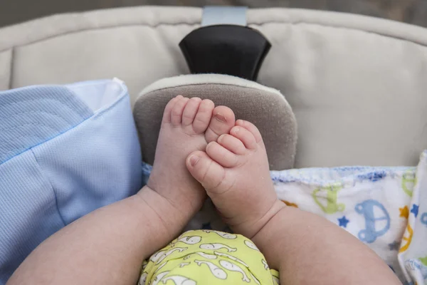 Pies de un bebé recién nacido en un cochecito — Foto de Stock