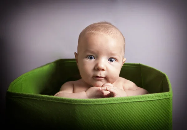 Chłopiec dziecko siedzi w zielone pudełko na zabawki — Zdjęcie stockowe