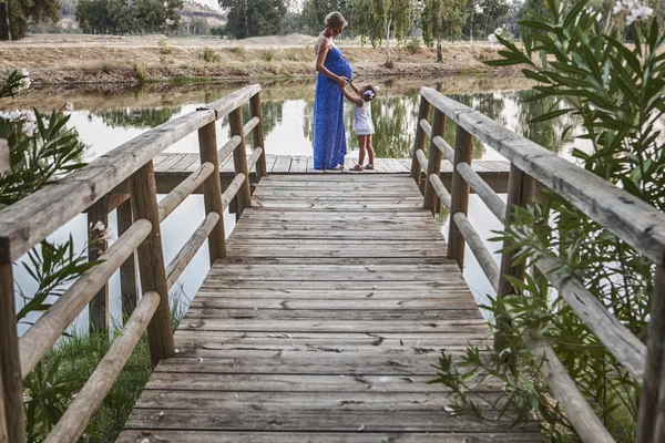 Pregnant mother and her daughter on pier — Stock Photo, Image