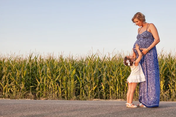 Mãe grávida e sua filha entre campos de milho — Fotografia de Stock