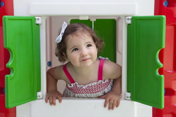 Meisje glimlachend door het raam van kinderen playhouse — Stockfoto