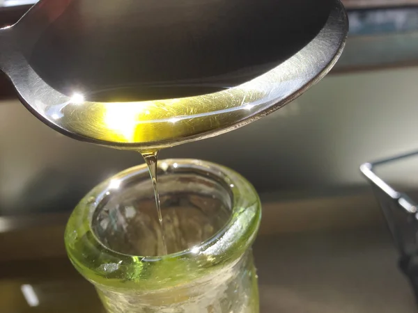 Pouring olive oil from the spoon — Stock Photo, Image