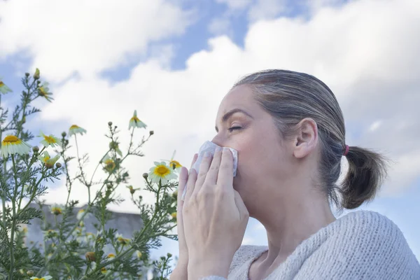 Woman sneezing in a daisy flowers meadow — Stock Photo, Image