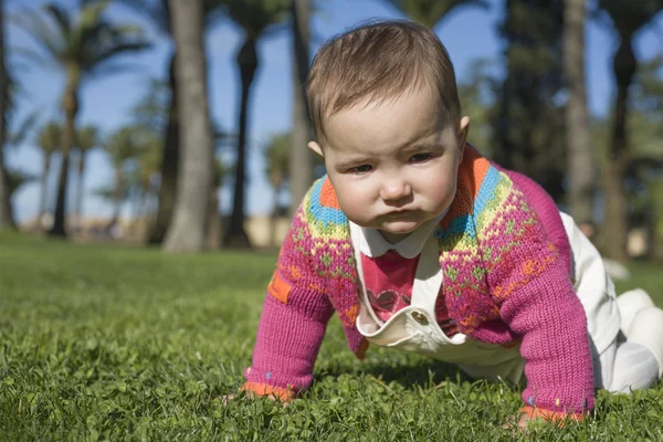 Baby flicka lära sig krypa på gräs park — Stockfoto