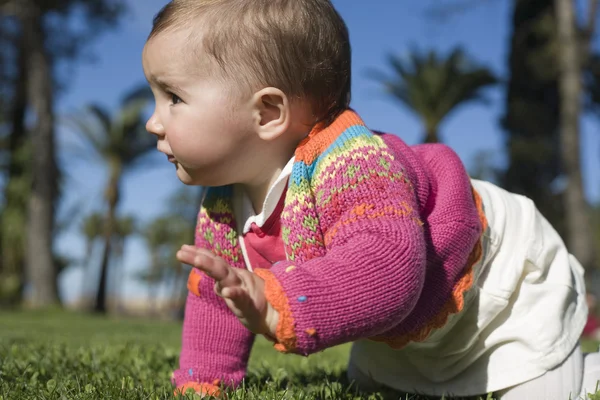 Menina aprendendo a rastejar no parque de grama — Fotografia de Stock