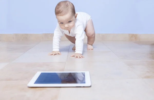 Babyjongen kruipen naar een tablet — Stockfoto