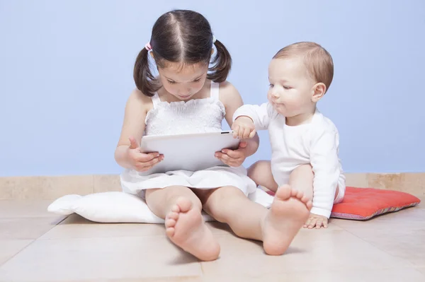 Babyjongen ontdekken van haar zus tablet pc — Stockfoto