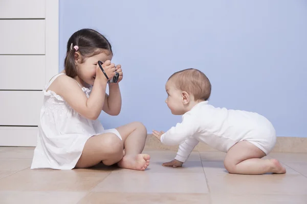 Pretty little sister taking pictures to her baby brother — Stock Photo, Image