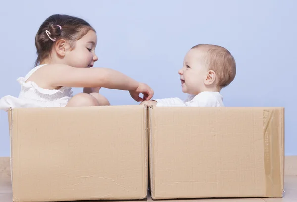 Маленькие братья играют с картонными коробками — стоковое фото