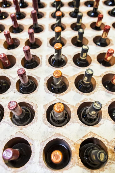Cantina file di bottiglie disposte su fori muro di mattoni — Foto Stock