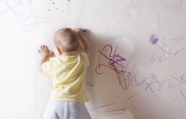 Мальчик рисует на гипсокартонной стене — стоковое фото