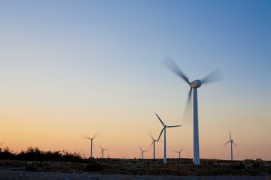 Elektrik Rüzgar türbinleri çiftliği kurak manzara günbatımı ışık ile