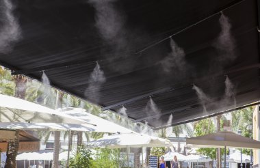 Awning sprinklers splashing water at terrace bar clipart