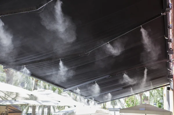 Aspersores toldo espirrando água no bar terraço — Fotografia de Stock