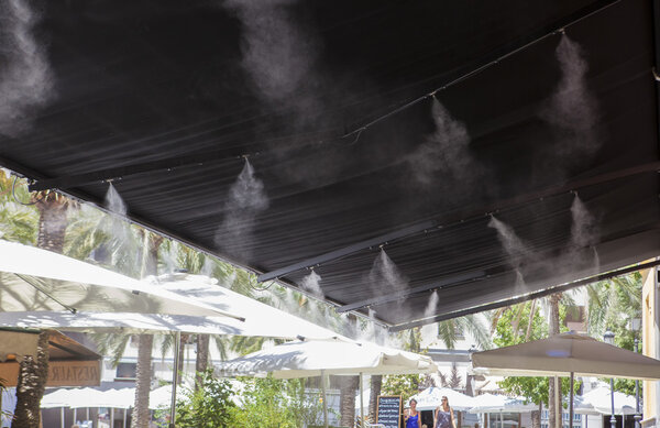 Awning sprinklers splashing water at terrace bar