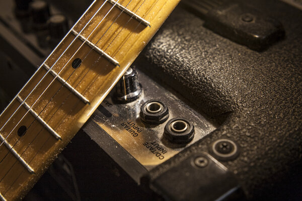 Electric guitar neck over amplifier device. Closeup