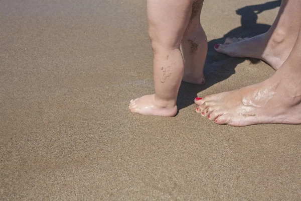 Madre y bebé pies caminando en la playa de arena —  Fotos de Stock