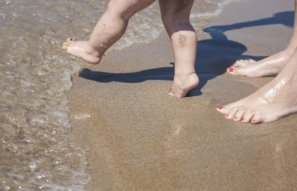 Madre y bebé pies caminando en la playa de arena —  Fotos de Stock