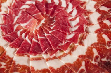 Circular decorative arrangement of iberian cured ham on plate clipart