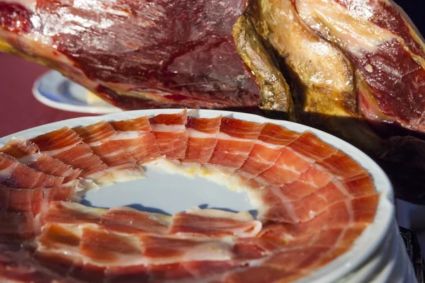 Iberian cured ham with slices plates beside — Stock Photo, Image