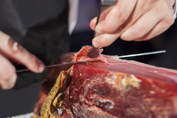 Master slicer tar Iberiska lufttorkad skinka med tång — Stockfoto