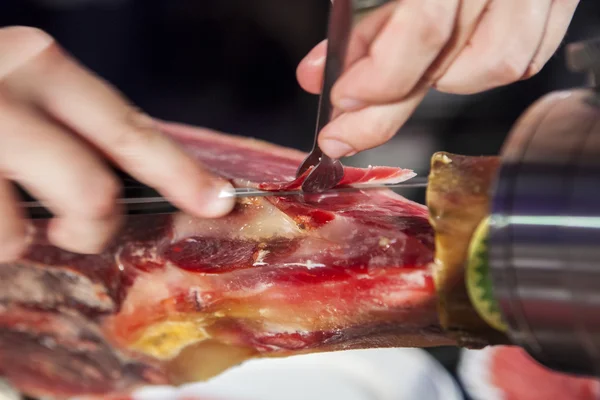 Master slicer taking iberian cured ham with tongs — Stock Photo, Image