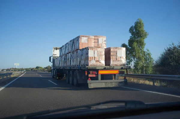 Driving behind building materials truck. View from the inside of the car